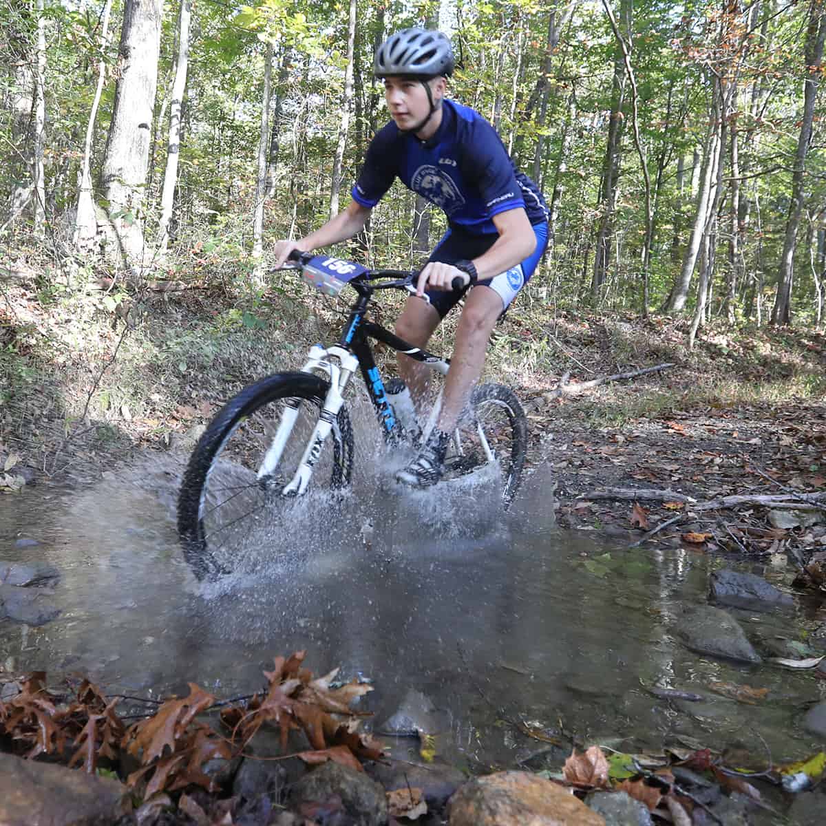 Mountain biker goes through a creek.